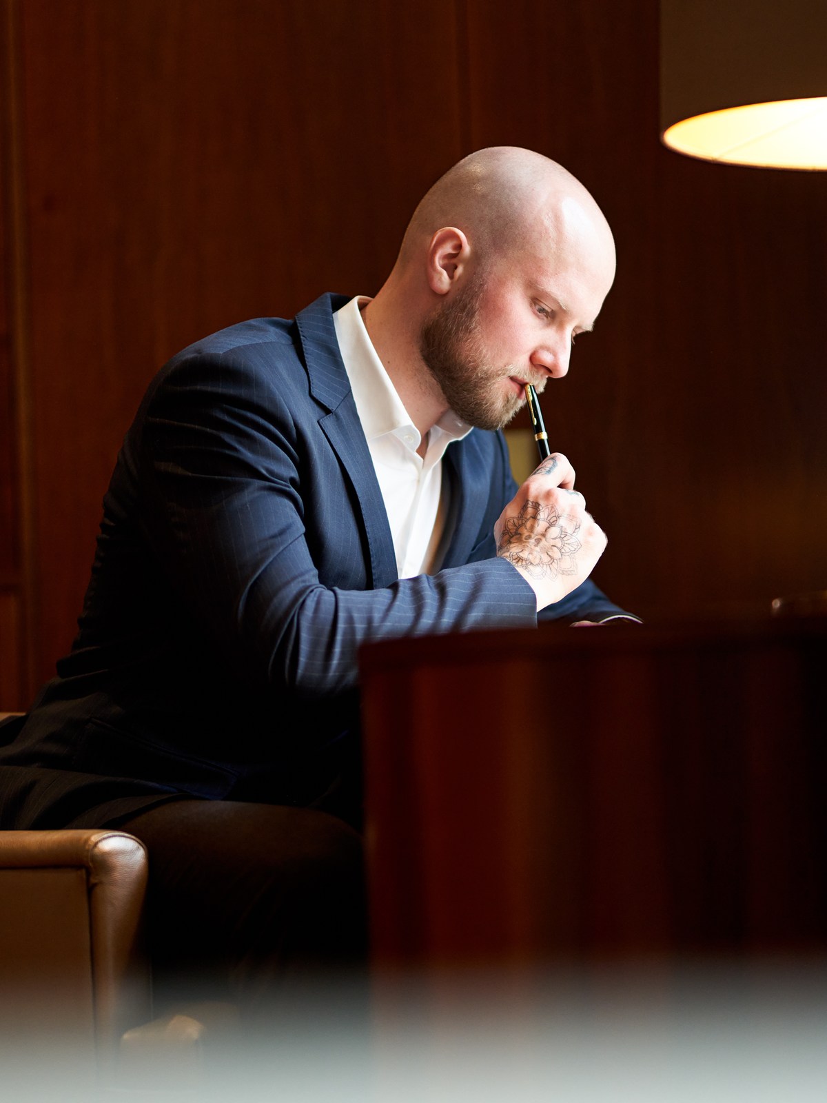 Florian Höper überlegt mit Stift in der Hand am Schreibtisch — inhaltliche Arbeit am Manuskript